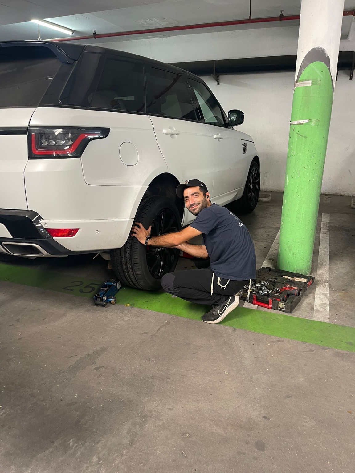 טכנאי מחליף גלגל ברכב פרטי בחניון