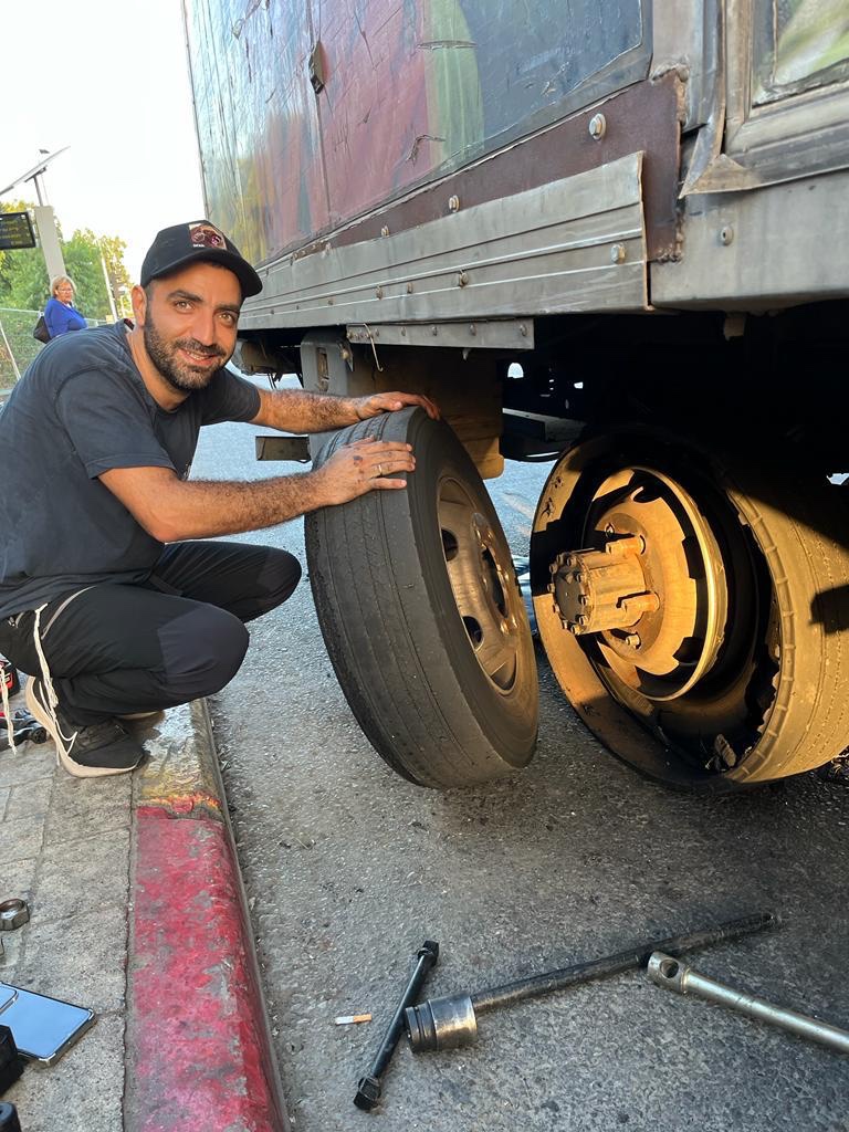טכנאי לצד גלגל משאית במהלך החלפה בדרך